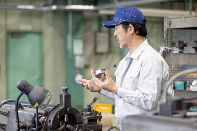 工場のベテラン職人が長年の経験で培った手の感覚と素材を確認する熟練の技術