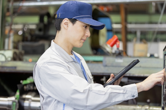 工場の生産管理モニターに表示される生産性低下データを見つめるDX推進担当者の困惑した表情