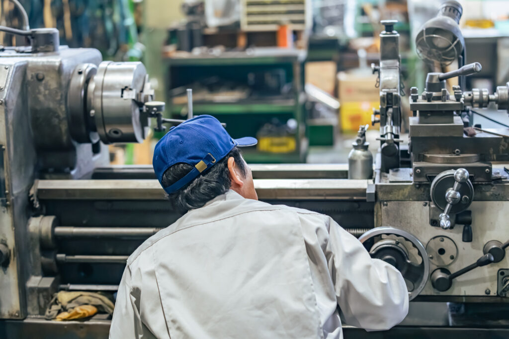 製造現場でタブレット入力に戸惑うベテラン作業員の後ろ姿