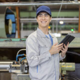 工場のデジタル化に期待を抱きタブレットで生産管理システムを見つめるDX推進担当者の希望に満ちた表情